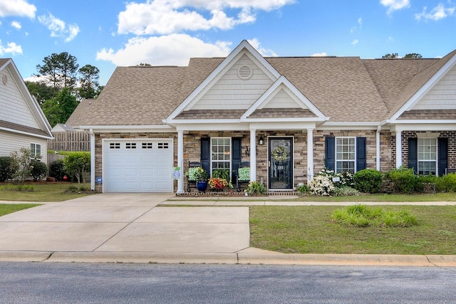 view of front of property featuring a front yard, a shingled roof, driveway, and stone siding
