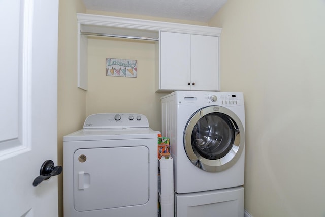 clothes washing area featuring washing machine and dryer and cabinet space