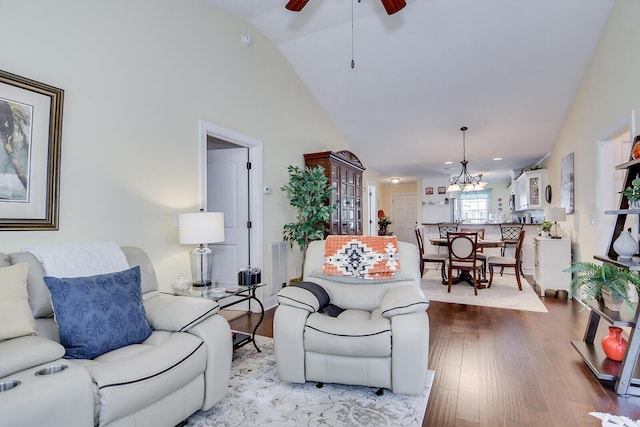 living area featuring a ceiling fan, wood finished floors, high vaulted ceiling, and a chandelier