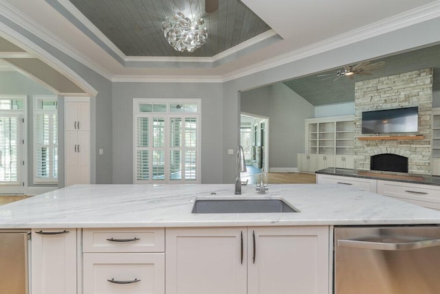 kitchen featuring light stone counters, white cabinetry, sink, and a tray ceiling