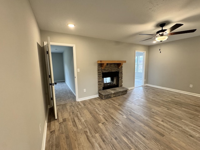 unfurnished living room featuring a fireplace, a textured ceiling, hardwood / wood-style flooring, and ceiling fan