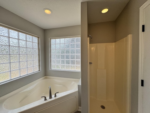 bathroom featuring a textured ceiling and independent shower and bath