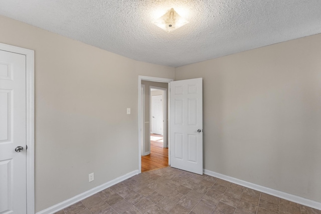 unfurnished bedroom featuring a textured ceiling and baseboards