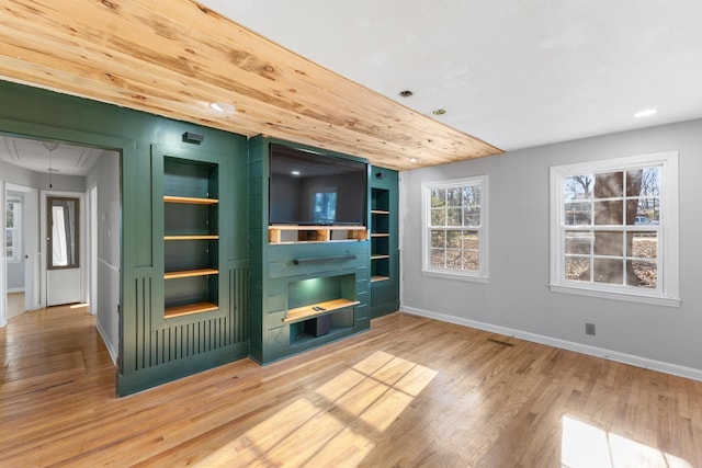 unfurnished living room featuring attic access, baseboards, built in features, wood finished floors, and recessed lighting