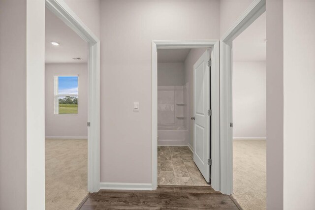 corridor featuring baseboards and carpet flooring