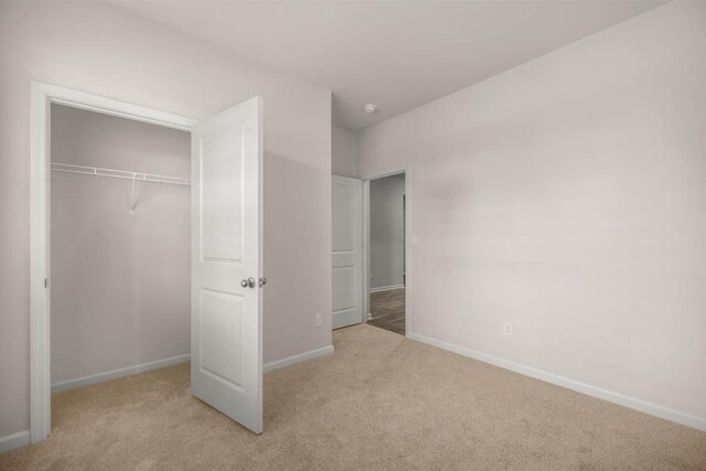 unfurnished bedroom featuring a closet, baseboards, and carpet