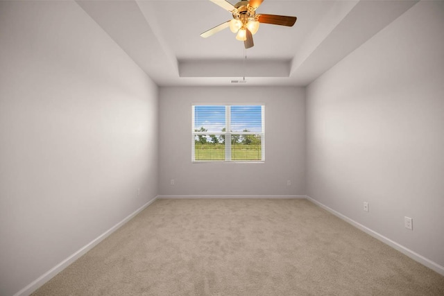 unfurnished room with visible vents, baseboards, a tray ceiling, light carpet, and a ceiling fan