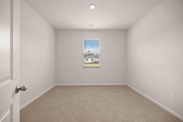 unfurnished room with visible vents, light colored carpet, and baseboards