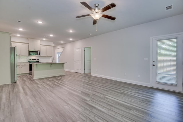 1056 Candleberry Dr, Grovetown, GA 30813 - kitchen featuring appliances with stainless steel finishes, light wood-style flooring, ceiling fan, open floor plan, and decorative backsplash