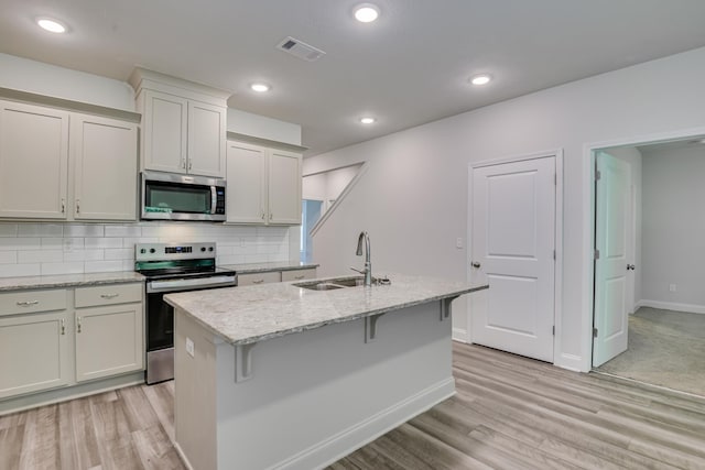 1056 Candleberry Dr, Grovetown, GA 30813 - kitchen with appliances with stainless steel finishes, a kitchen island with sink, light wood-type flooring, tasteful backsplash, and recessed lighting