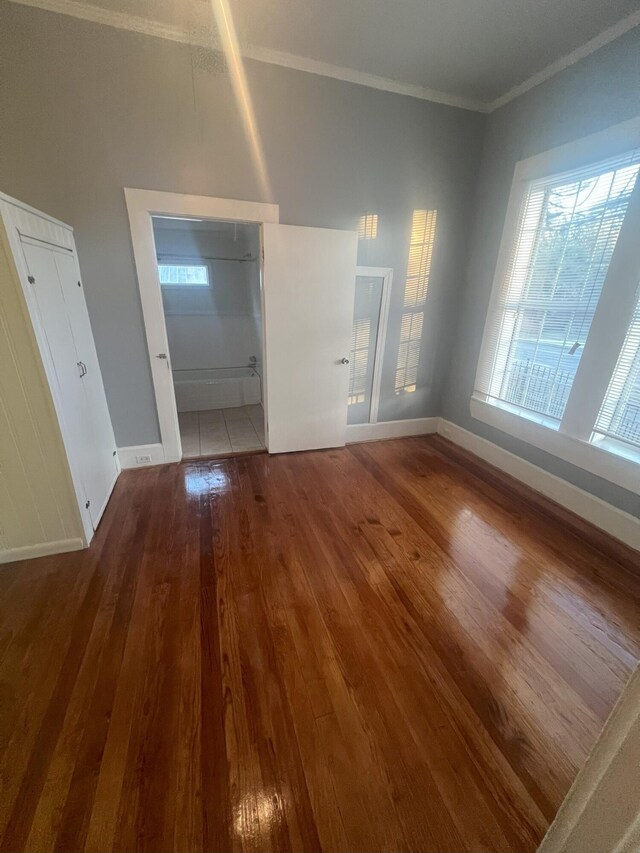 interior space with hardwood / wood-style floors, crown molding, connected bathroom, and multiple windows