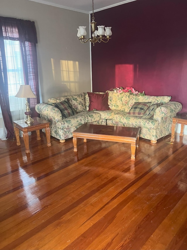 living room featuring wood-type flooring, an inviting chandelier, and ornamental molding