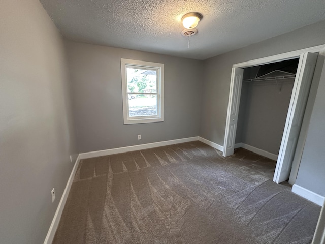 unfurnished bedroom featuring a closet, dark carpet, and a textured ceiling