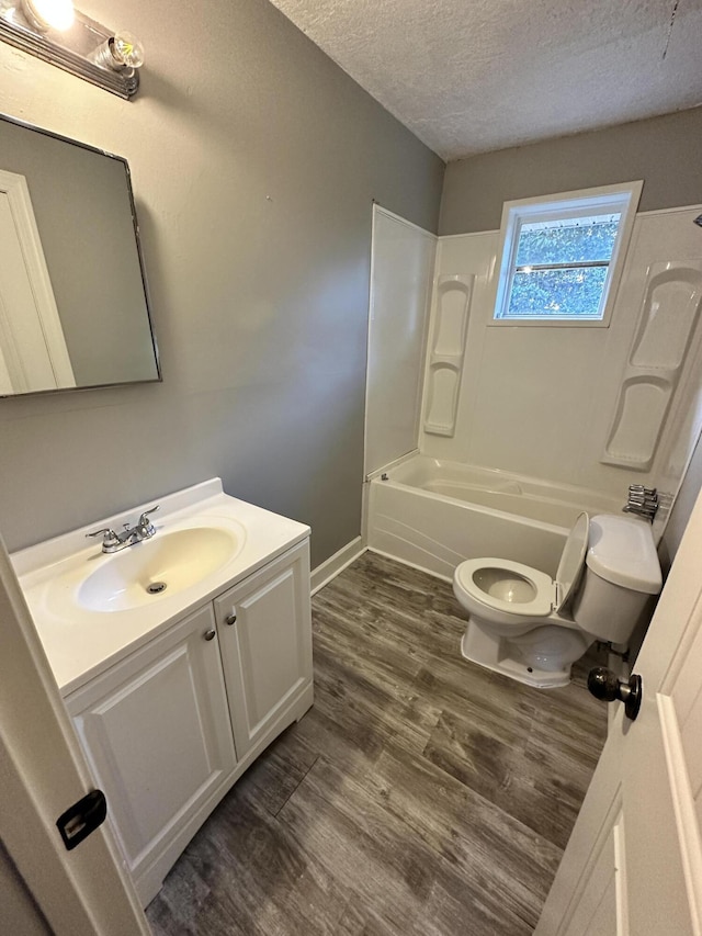 full bathroom with hardwood / wood-style floors, shower / bath combination, a textured ceiling, toilet, and vanity