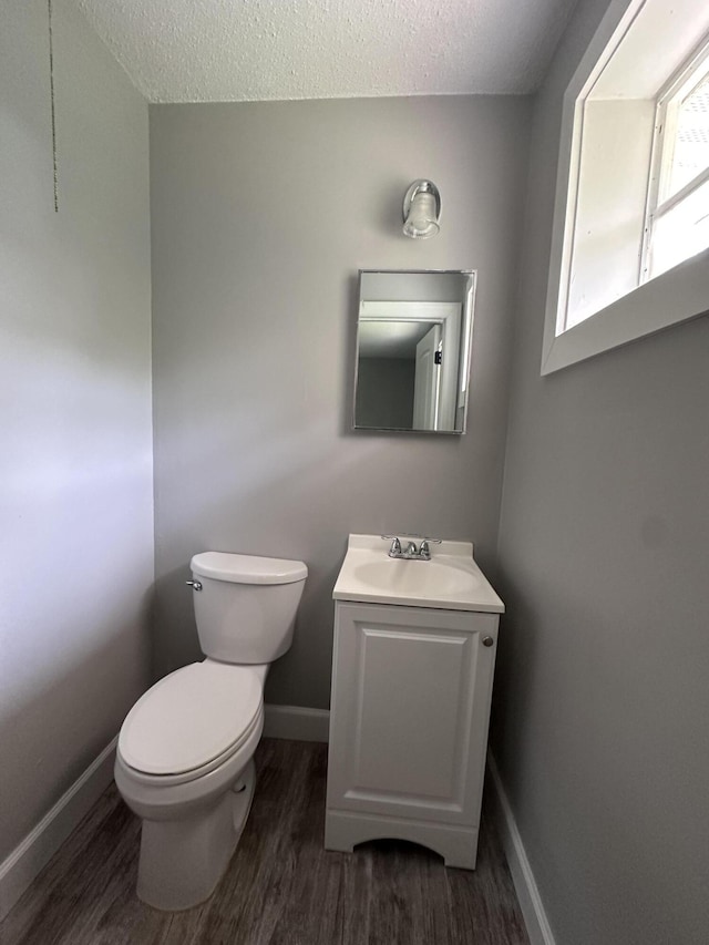 bathroom featuring vanity, hardwood / wood-style floors, a textured ceiling, and toilet