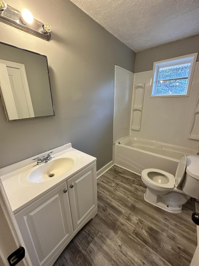 full bathroom featuring vanity, a textured ceiling, washtub / shower combination, hardwood / wood-style floors, and toilet