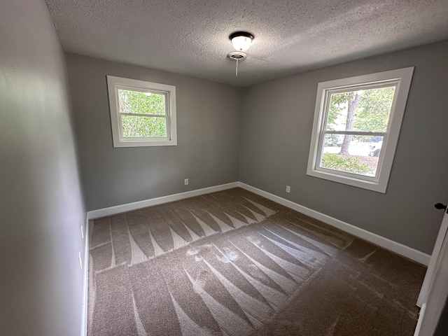 carpeted empty room with a textured ceiling