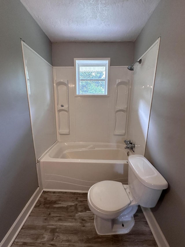 bathroom featuring hardwood / wood-style flooring, toilet, a textured ceiling, and tub / shower combination