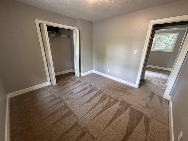 unfurnished bedroom with a textured ceiling, carpet floors, and a closet