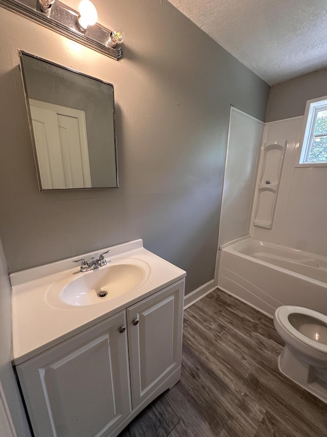 full bathroom featuring wood-type flooring, a textured ceiling, toilet, shower / tub combination, and vanity