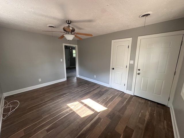 empty room with a textured ceiling, dark hardwood / wood-style floors, and ceiling fan