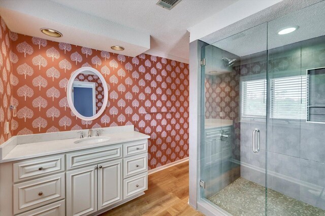 bathroom featuring vanity, an enclosed shower, wood-type flooring, and a textured ceiling