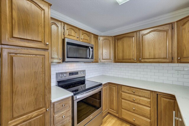 kitchen featuring backsplash, light hardwood / wood-style flooring, ornamental molding, a textured ceiling, and stainless steel appliances