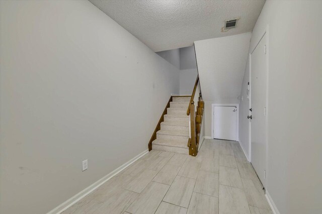 staircase featuring a textured ceiling