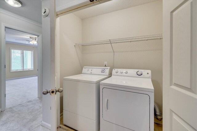 clothes washing area with washer and clothes dryer, light carpet, crown molding, ceiling fan, and a textured ceiling