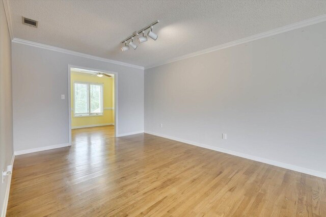 unfurnished room with light wood-type flooring, a textured ceiling, rail lighting, and ornamental molding