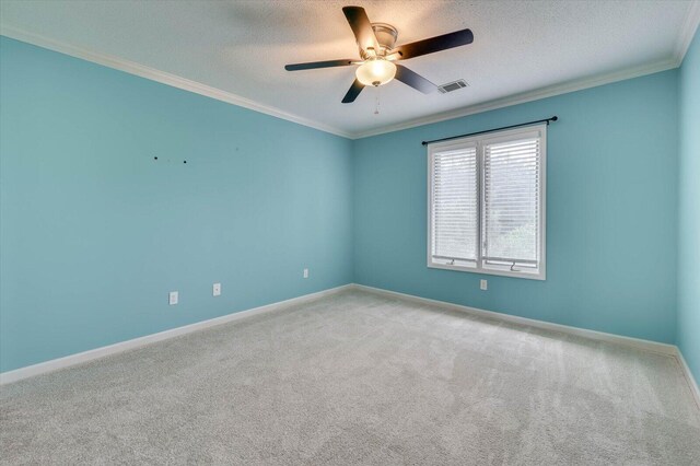 spare room featuring ceiling fan, light colored carpet, ornamental molding, and a textured ceiling