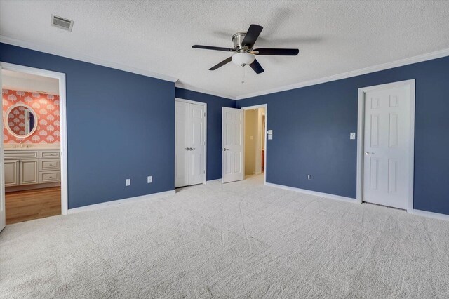 unfurnished bedroom with connected bathroom, ceiling fan, light colored carpet, and ornamental molding