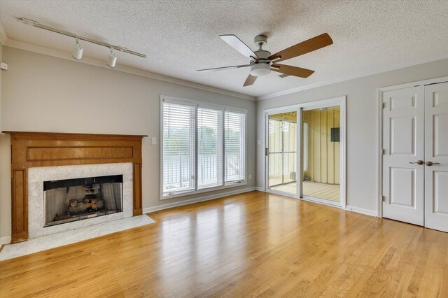 unfurnished living room with ceiling fan, crown molding, rail lighting, and a textured ceiling