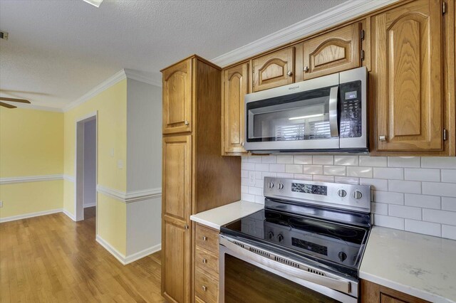 kitchen featuring tasteful backsplash, stainless steel appliances, a textured ceiling, and ornamental molding