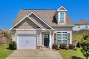 view of front of home with a front lawn, concrete driveway, fence, and an attached garage