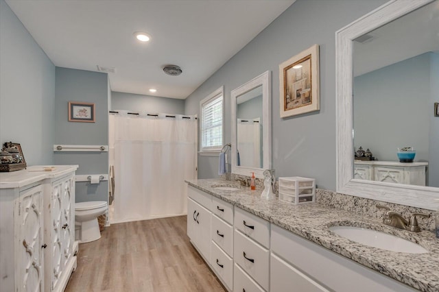 bathroom featuring walk in shower, hardwood / wood-style flooring, vanity, and toilet