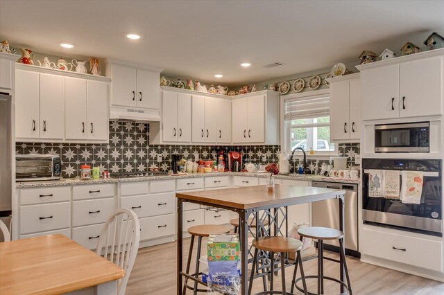 kitchen featuring white cabinets, sink, light wood-type flooring, appliances with stainless steel finishes, and custom range hood