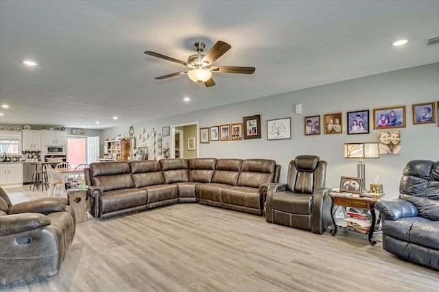 living room with light wood-type flooring, ceiling fan, and sink