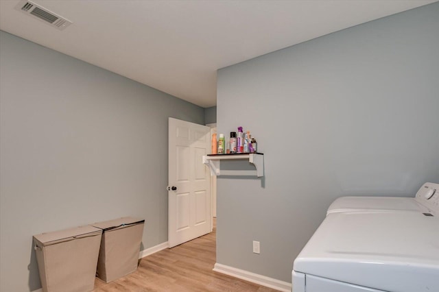 laundry area with washer and dryer and light hardwood / wood-style flooring