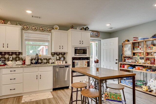 kitchen with decorative backsplash, appliances with stainless steel finishes, white cabinetry, and sink