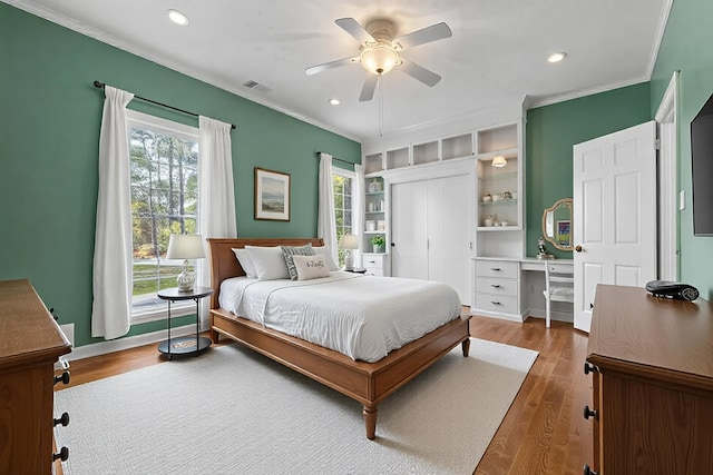 bedroom featuring crown molding, hardwood / wood-style floors, ceiling fan, and a closet