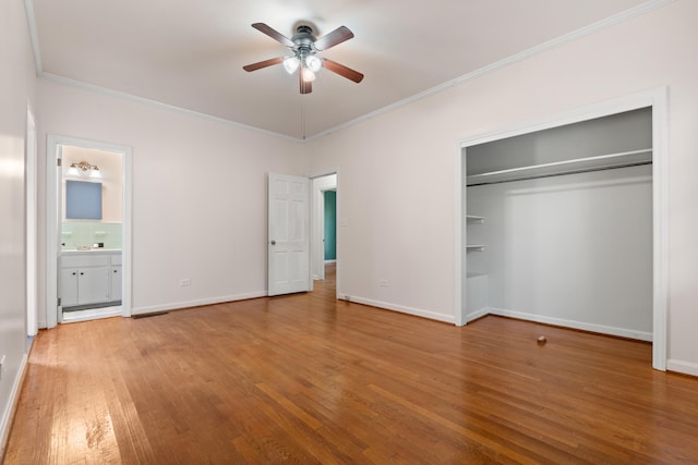 unfurnished bedroom with crown molding, ceiling fan, connected bathroom, wood-type flooring, and a closet