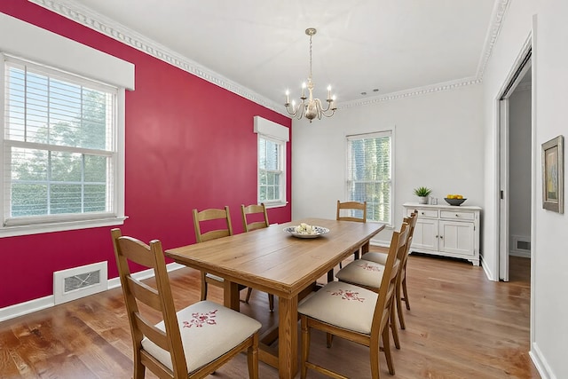 dining area with ornamental molding, hardwood / wood-style floors, and a chandelier