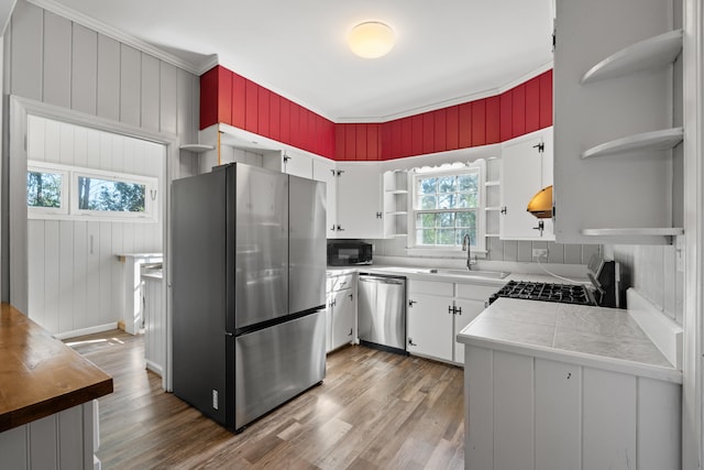 kitchen with appliances with stainless steel finishes, sink, light hardwood / wood-style flooring, and white cabinets