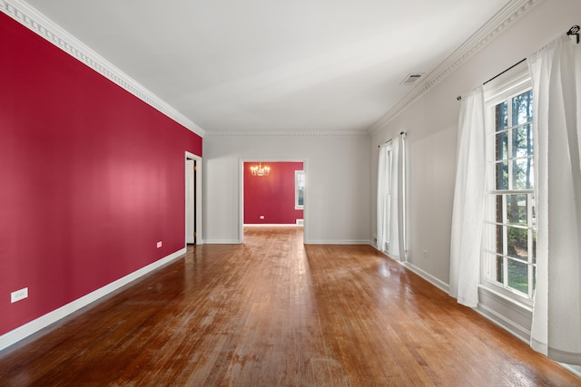 spare room with an inviting chandelier, hardwood / wood-style floors, and crown molding