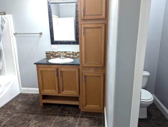 full bath with tasteful backsplash, baseboards, toilet, a bathing tub, and vanity