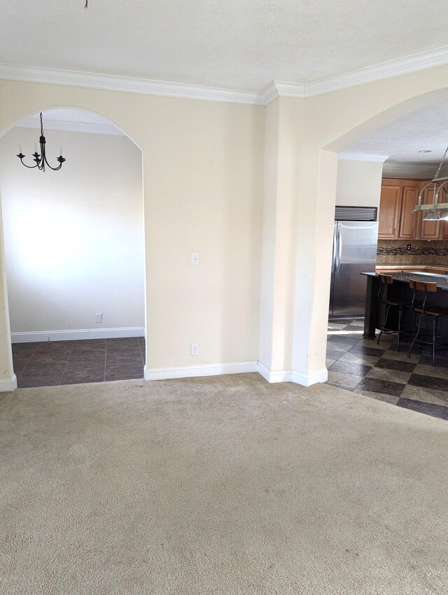 unfurnished room with a chandelier, dark carpet, and ornamental molding