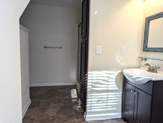 bathroom with stone finish flooring, vanity, and baseboards