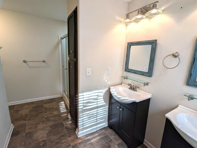 full bath featuring a stall shower, stone finish flooring, vanity, and baseboards