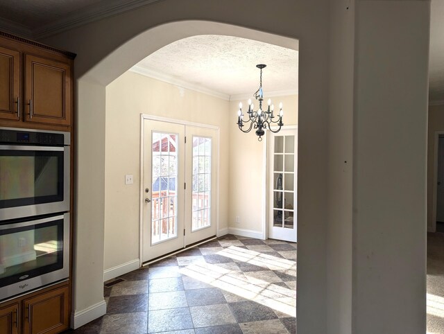 doorway featuring ornamental molding, arched walkways, baseboards, and stone tile floors